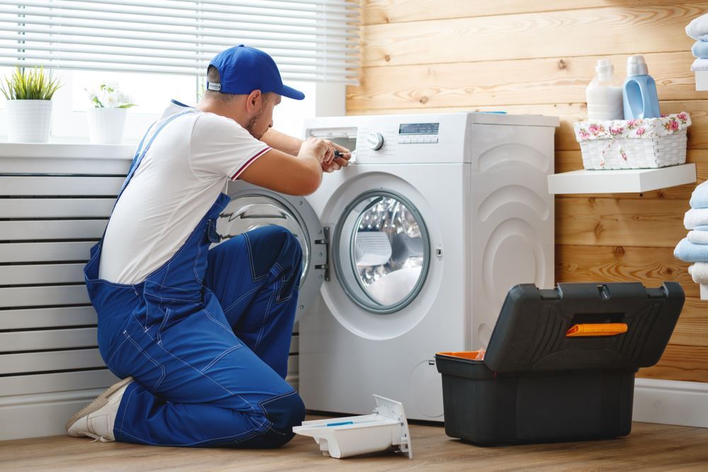 Appliance repair professional working beside a household washing machine