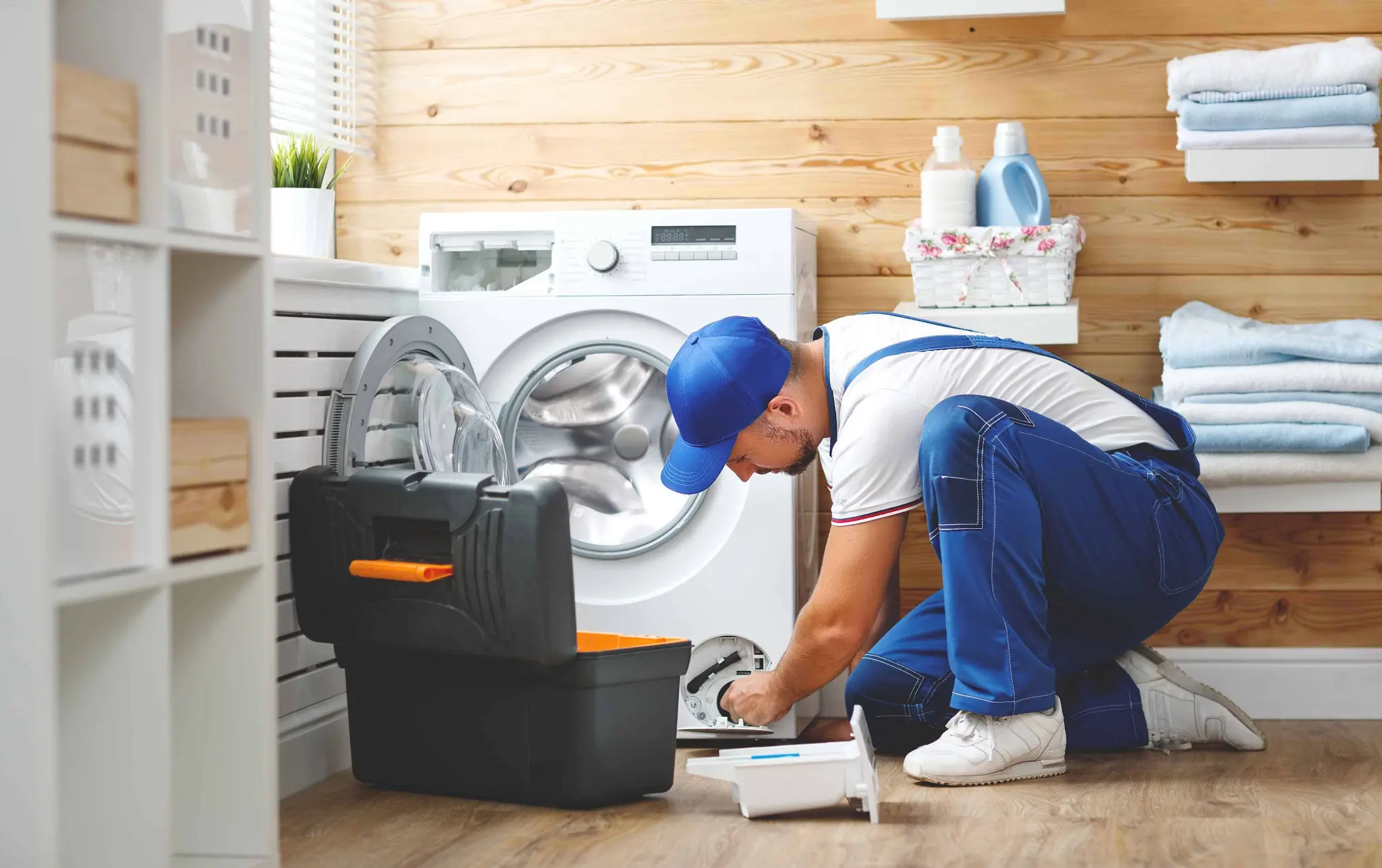 Appliance repair professional working on a household appliance in a residential laundry room