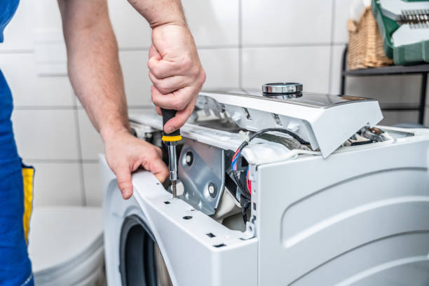 Close-up of an appliance repair professional opening a washing machine control panel